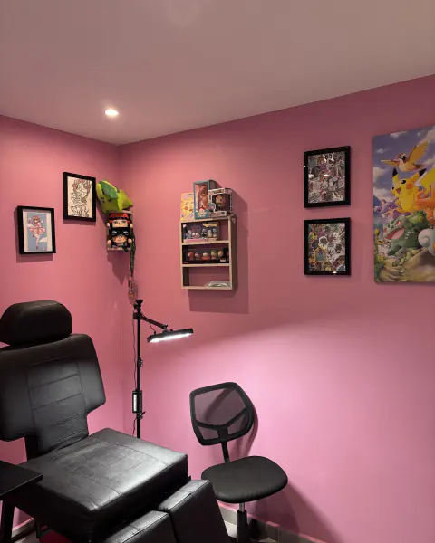 Cabina de tatuaje con paredes rosadas y camilla